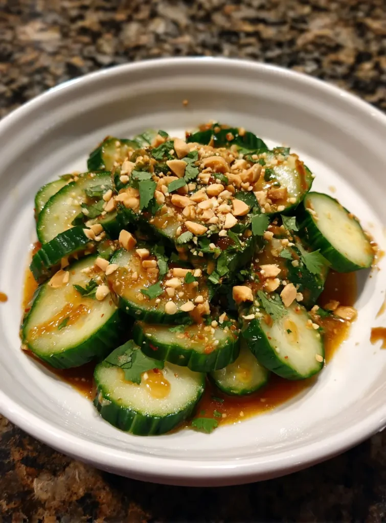 Peanut Butter Cucumber Salad Recipe – 1 Easy Dish That Shocks You 4 Overhead view of peanut butter cucumber salad with sliced cucumbers, creamy peanut sauce, and garnished with sesame seeds and cilantro.