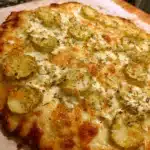 Pickle Pizza Recipe: A Tangy, Cheesy Favorite Everyone Will Love 5 Whole freshly baked pickle pizza on parchment paper with bubbling cheese and vibrant green pickle slices.